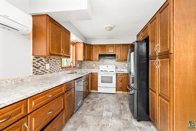 kitchen featuring a wall unit AC, light wood-type flooring, sink, decorative backsplash, and appliances with stainless steel finishes