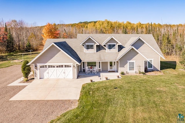 view of front of home featuring covered porch, a garage, and a front lawn