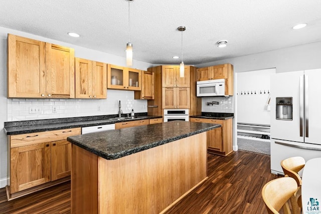 kitchen featuring white appliances, sink, hanging light fixtures, dark hardwood / wood-style floors, and a kitchen island