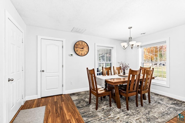 dining room featuring a chandelier, a textured ceiling, and dark hardwood / wood-style floors