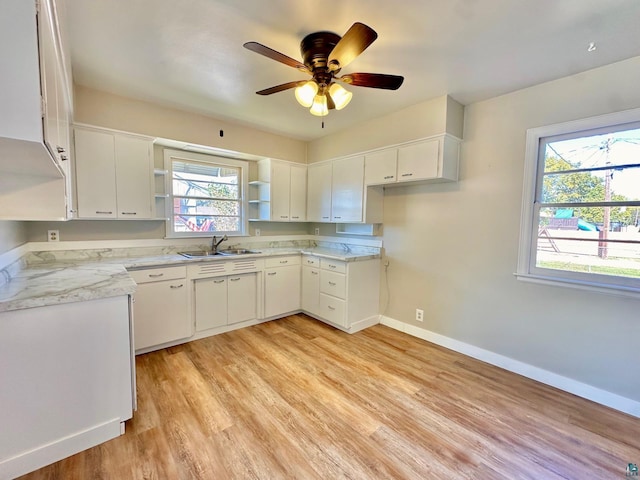 kitchen featuring a healthy amount of sunlight, light hardwood / wood-style floors, sink, and white cabinetry