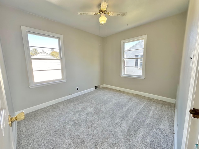 carpeted spare room with ceiling fan and plenty of natural light