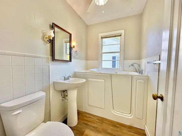 bathroom with a bathtub, toilet, tile walls, and hardwood / wood-style floors