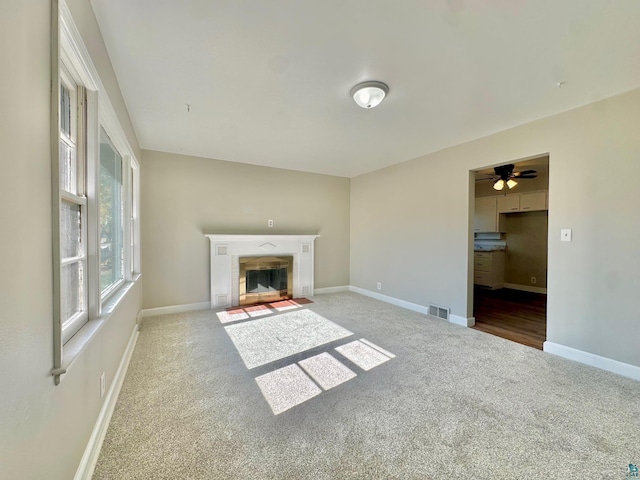 unfurnished living room with ceiling fan and carpet