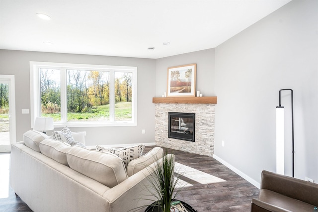 living room featuring dark wood-type flooring and a stone fireplace