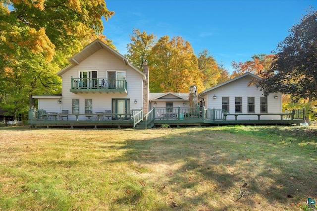 back of house featuring a balcony, a deck, and a lawn