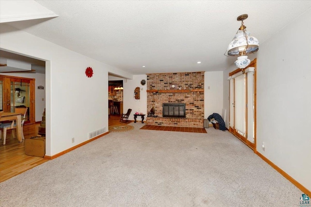 unfurnished living room with a textured ceiling, carpet, and a brick fireplace