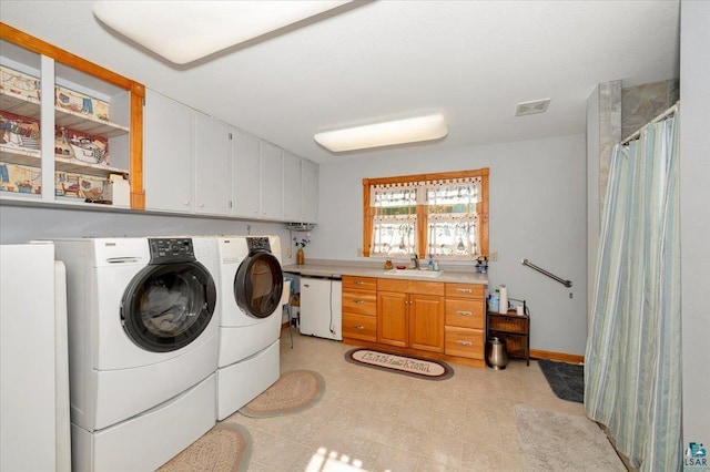 washroom with cabinets, sink, and washing machine and dryer