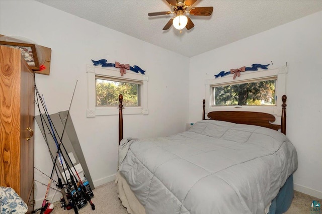 bedroom featuring light carpet, a textured ceiling, and ceiling fan