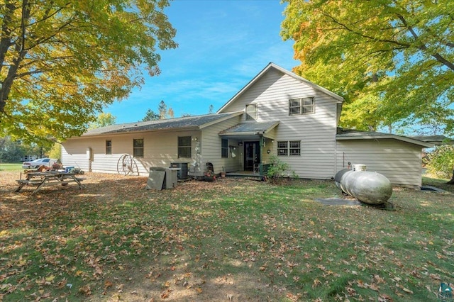 back of house featuring central air condition unit and a lawn