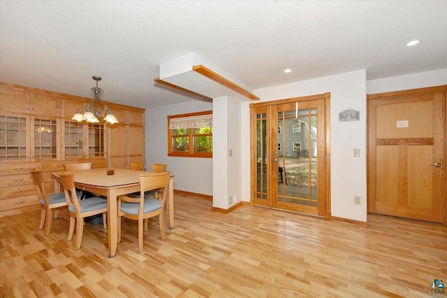 dining room featuring a textured ceiling, light hardwood / wood-style flooring, and a chandelier