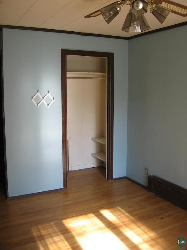 unfurnished bedroom with ornamental molding, hardwood / wood-style flooring, a closet, and ceiling fan