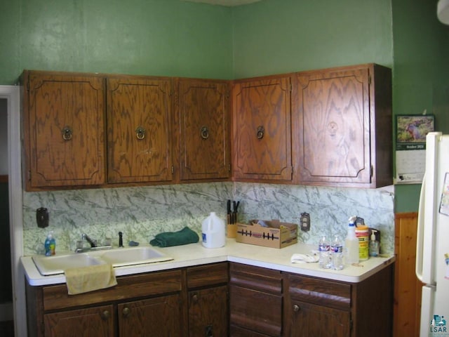 kitchen with decorative backsplash, sink, and white refrigerator