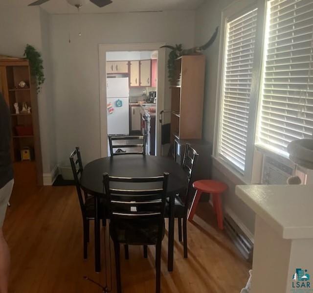 dining area with a baseboard heating unit, light wood-type flooring, and ceiling fan