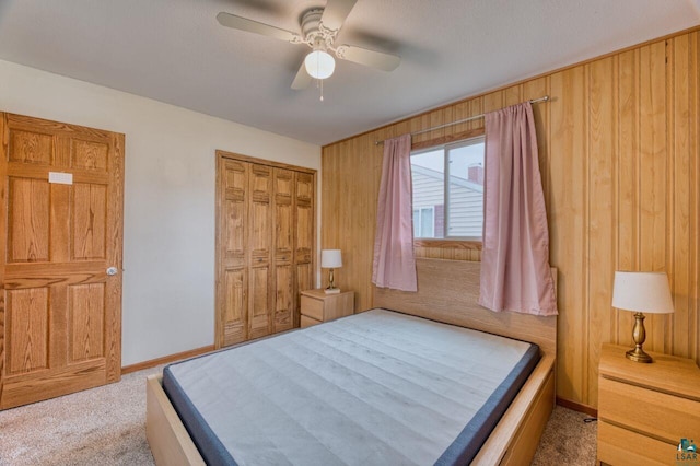 carpeted bedroom featuring a closet, wood walls, and ceiling fan