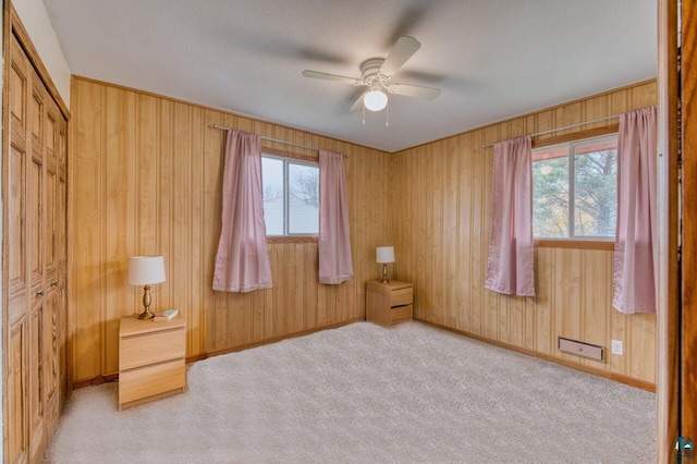 unfurnished bedroom with light carpet, multiple windows, and ceiling fan