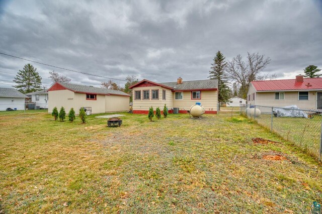 rear view of property featuring a yard and a fire pit