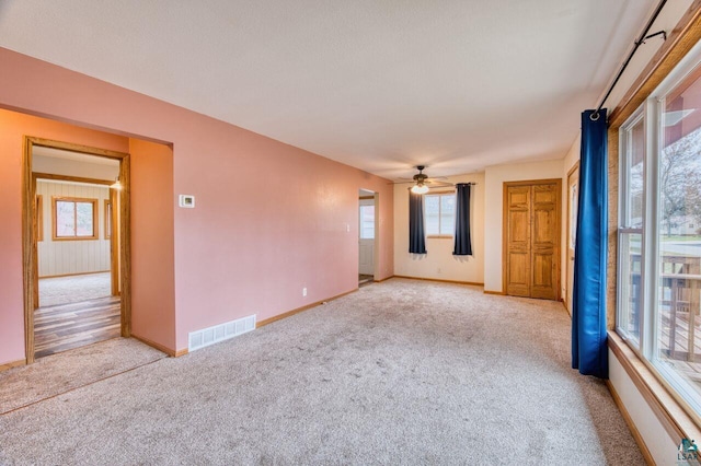 carpeted empty room featuring ceiling fan and a wealth of natural light