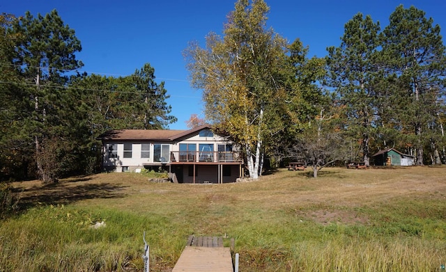 rear view of property featuring a yard and a wooden deck