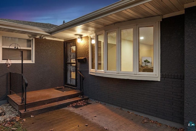 exterior entry at dusk featuring a wooden deck