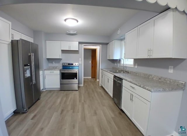 kitchen with sink, white cabinetry, stainless steel appliances, and light hardwood / wood-style floors