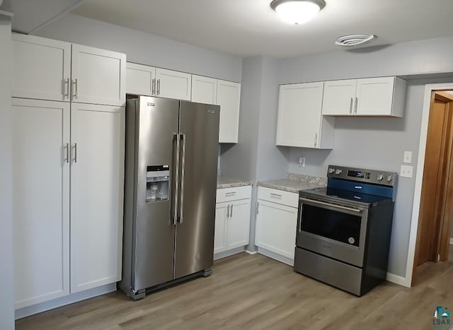 kitchen with light stone counters, white cabinets, stainless steel appliances, and light wood-type flooring