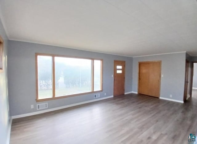 unfurnished living room with dark wood-type flooring and crown molding