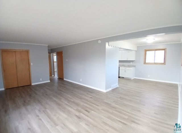 unfurnished living room with crown molding and light hardwood / wood-style flooring