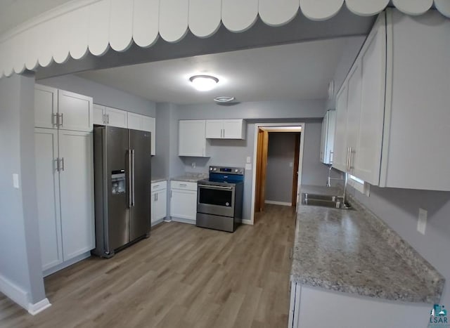 kitchen with sink, stainless steel appliances, white cabinets, light stone counters, and light hardwood / wood-style flooring