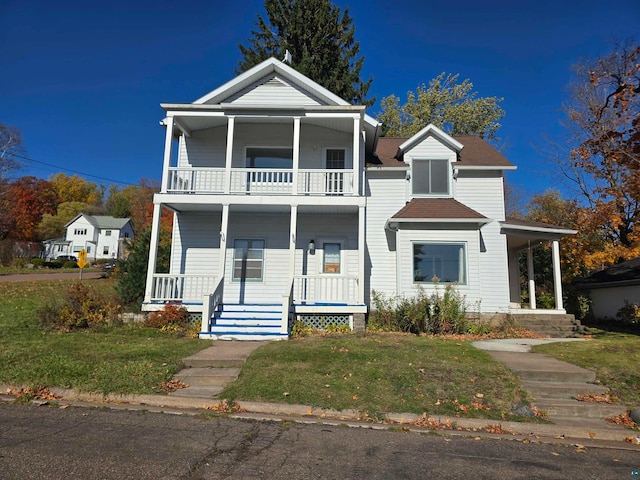 view of front of home with a balcony, a front yard, and a porch