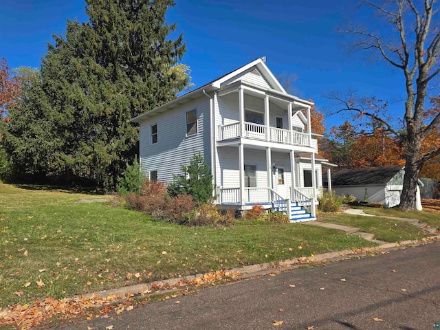 view of front of home with a balcony, covered porch, and a front lawn