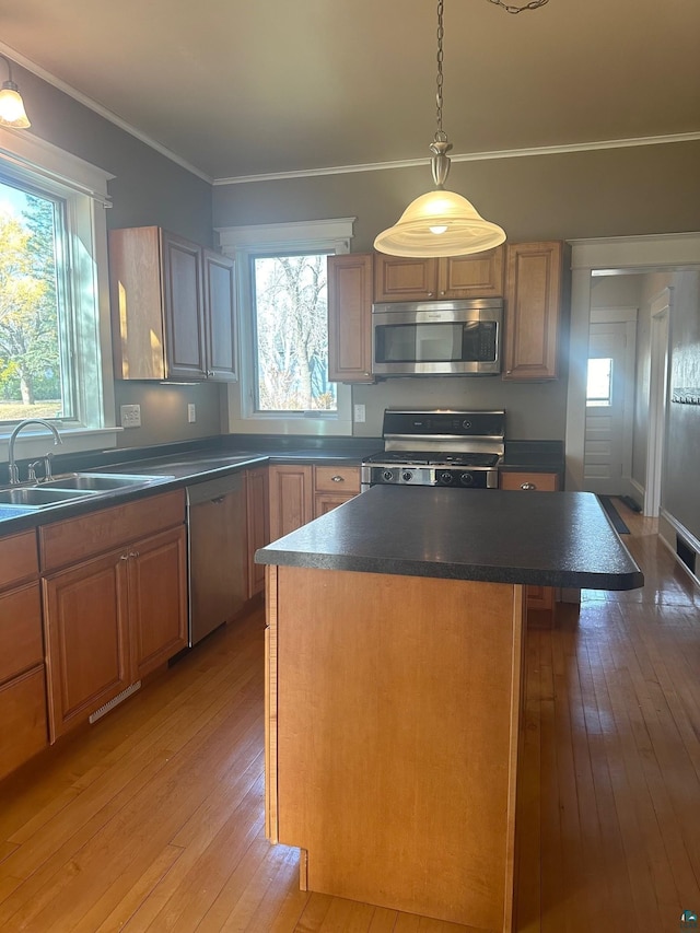 kitchen with sink, a kitchen island, light hardwood / wood-style floors, stainless steel appliances, and ornamental molding