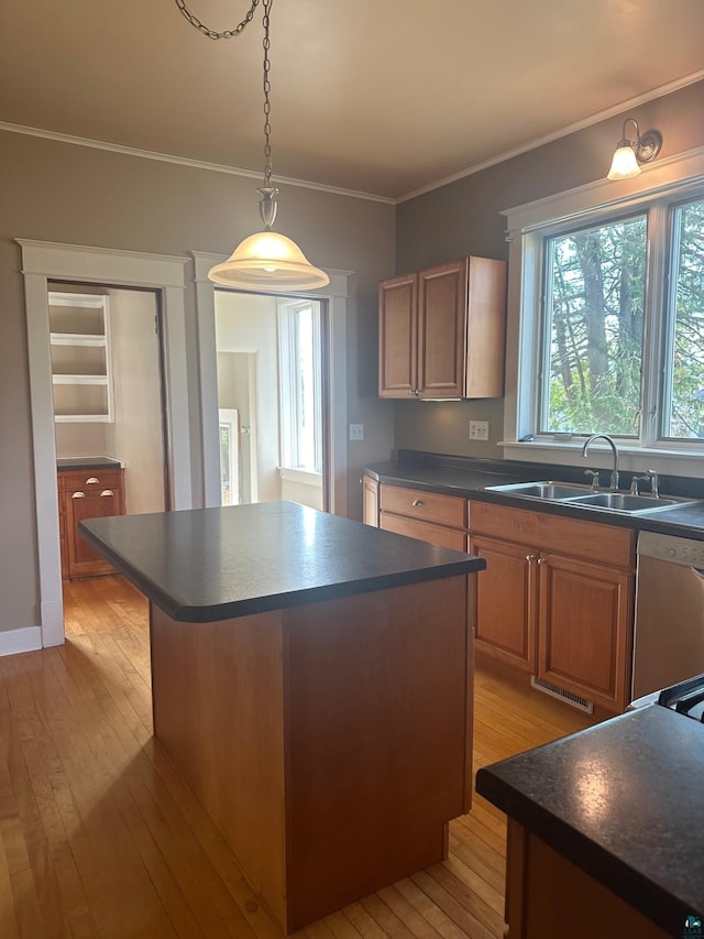 kitchen featuring sink, a kitchen island, stainless steel dishwasher, ornamental molding, and light hardwood / wood-style flooring