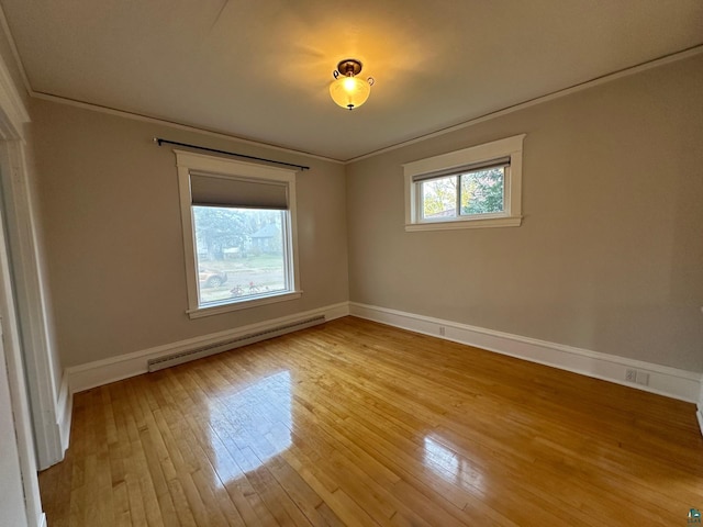 spare room featuring ornamental molding, a baseboard radiator, and light wood-type flooring