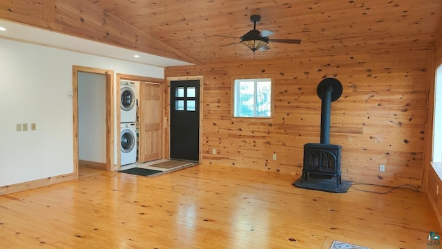 entryway featuring hardwood / wood-style floors, wooden ceiling, vaulted ceiling, stacked washer / drying machine, and a wood stove