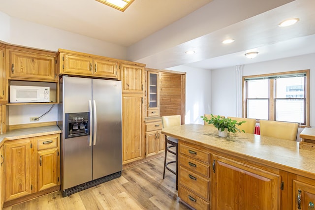 kitchen with stainless steel fridge, light wood-type flooring, and a breakfast bar