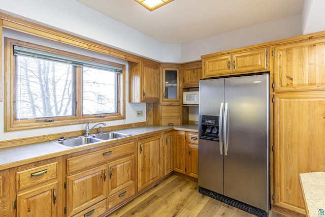 kitchen with light wood-type flooring, sink, and stainless steel fridge