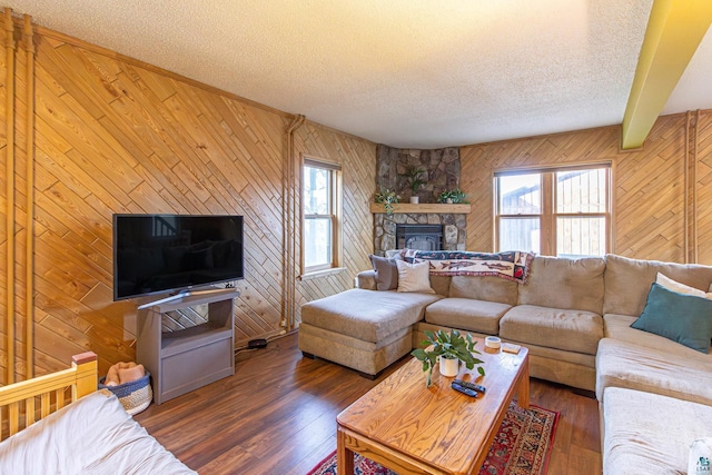 living room featuring dark wood-type flooring, a textured ceiling, and wooden walls