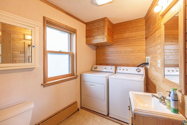 laundry room with wood walls, sink, a textured ceiling, independent washer and dryer, and a baseboard heating unit