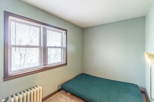 carpeted bedroom with radiator heating unit and a textured ceiling