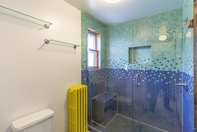 bathroom featuring radiator heating unit, toilet, and a shower with door