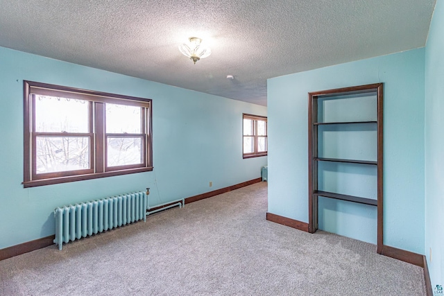 carpeted empty room with radiator, a textured ceiling, and a wealth of natural light