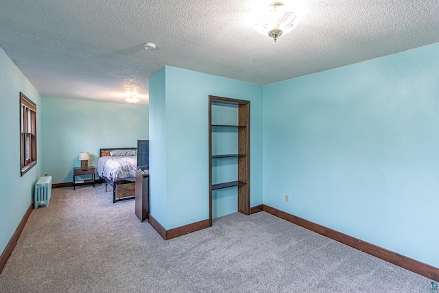 bedroom featuring a textured ceiling, radiator heating unit, and carpet