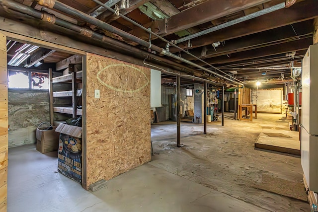 basement featuring water heater and white fridge