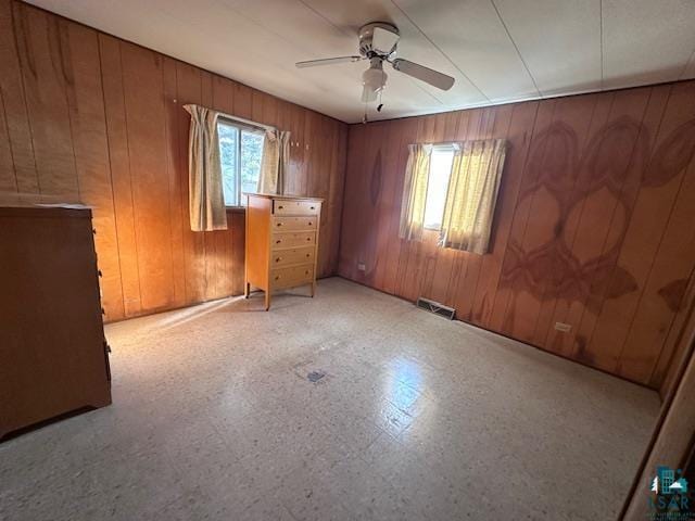 empty room featuring wood walls and ceiling fan