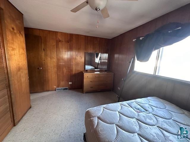 bedroom with wooden walls, ceiling fan, and a closet