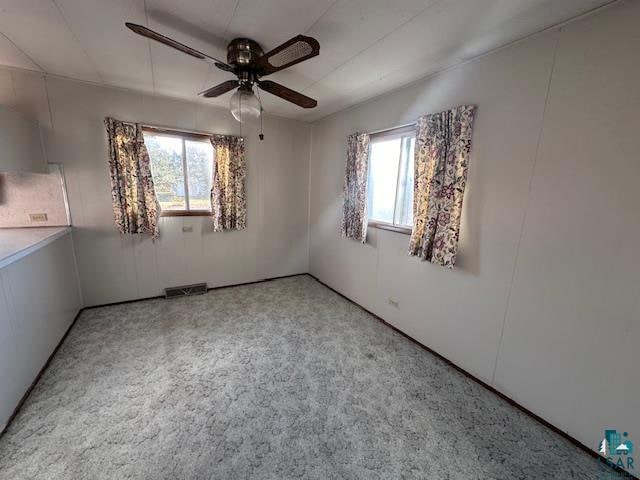 carpeted spare room featuring ceiling fan