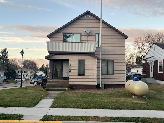 view of front of house with a balcony and a yard