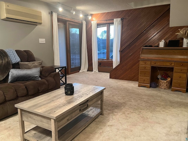 carpeted living room featuring track lighting, wood walls, a textured ceiling, and a wall mounted AC