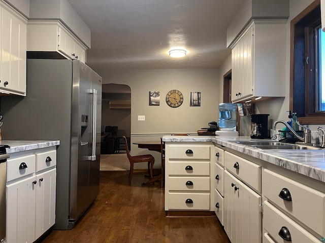 kitchen with dark wood-type flooring, white cabinets, kitchen peninsula, sink, and stainless steel fridge